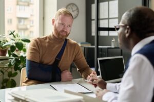 An experienced motorcycle accident lawyer in Defiance, discussing legal options with an injured client who has their arm in a sling.